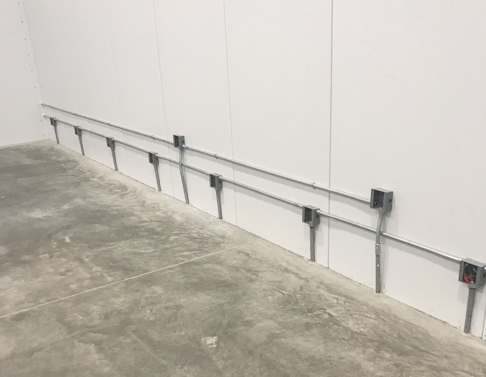 Junction boxes and conduit risers along a freezer wall
